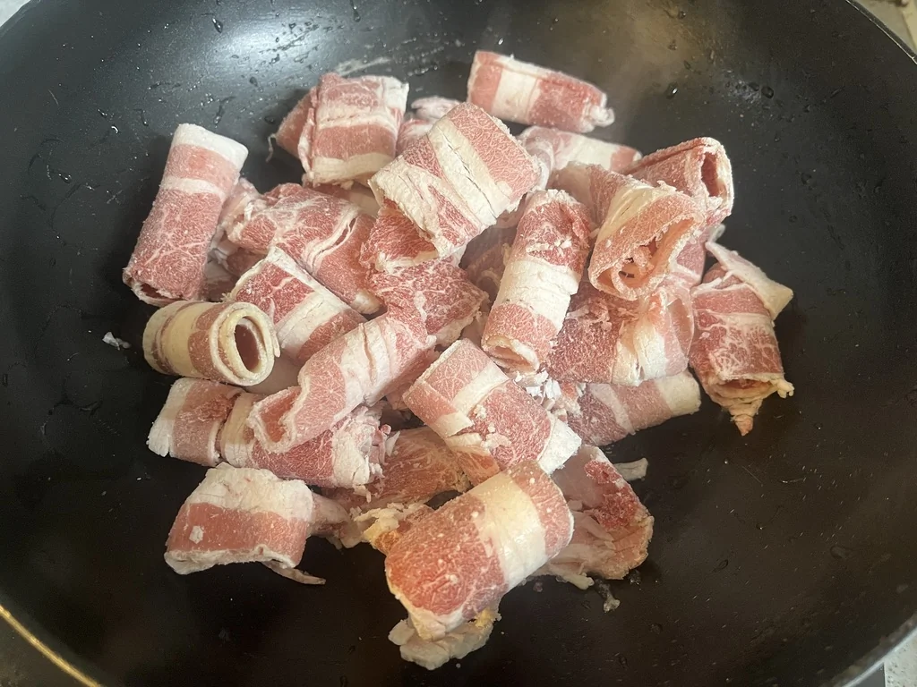 Thinly sliced usamgyeop beef brisket stir-frying in a pan for doenjang sulbap